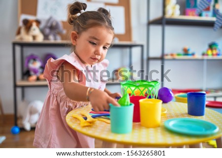 Young beautiful toddler playing with cutlery and food toys on the table at kindergaten