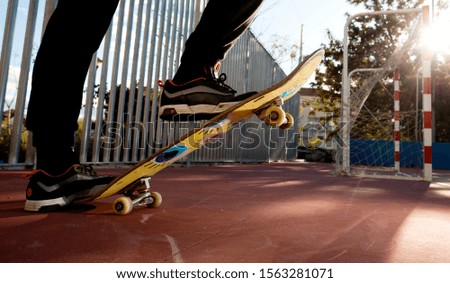 The young individual legs of the male skateboarder only skateboard in an urban area in a skatepark with long black pants and sneakers with metal fences in the background