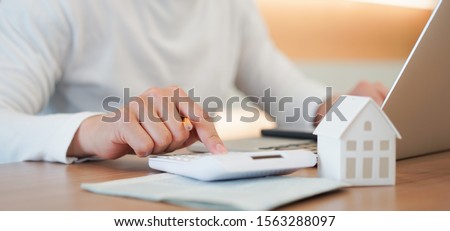 close up young man hand press on calculator to check and summary expense of home loan mortgage for refinance plan , people lifestyle concept Royalty-Free Stock Photo #1563288097