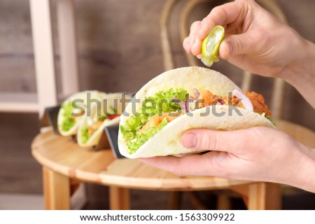 Woman squeezing lime on fish taco indoors, closeup