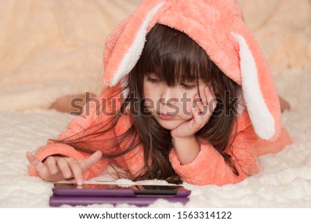 Girl playing with an internet tablet. Little girl of five years old using digital tablet and playing in bed