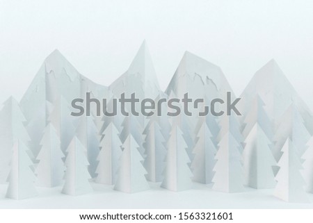 White winter paper landscape with mountains and pine trees 