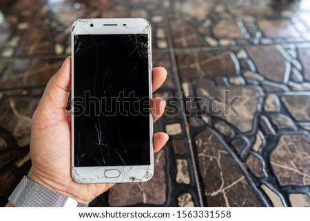Cracked and broken mobile phone on hand and blurred background, smartphone cover glass screen crash, break down mobile telephone damage to repair