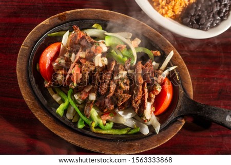 sizzling beef fajita platter in skillet Royalty-Free Stock Photo #1563333868