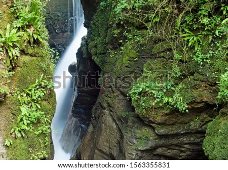waterfall in canyon river gorge and moss covered rocks