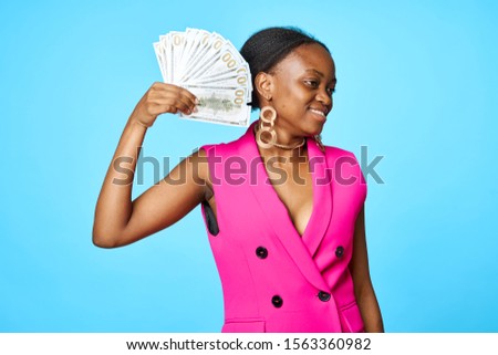 fashionable woman in earrings and a pink shirt with a bundle of money in her hand