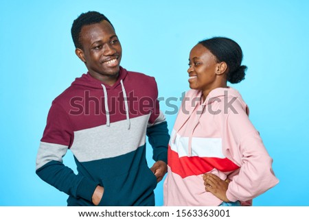 African American in a sweater and a black woman look at each other on a blue background