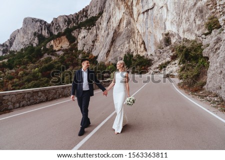 Young newly wed couple, bride and groom kissing, hugging on perfect view of mountains, wedding concept