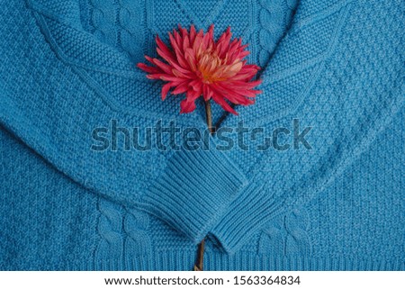 Pattern of colorful knitted sweaters closeup. Handmade merino wool product. A stack of folded clothes with flowers