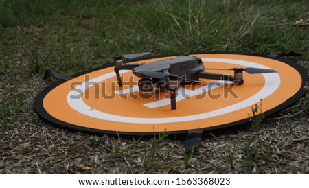 The Drone taking off position above on landing pada at the grass field in the sunny day. 