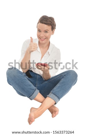 Girl with red phone in white shirt and blue jeans showing thumb up. Smiling woman isolated on white background.
