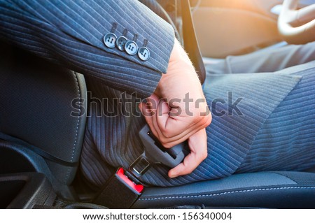 Driver in business suit fastens his seat himself automobile seat belt Royalty-Free Stock Photo #156340004
