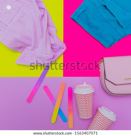 Fashionable laid out set: pink denim jacket, handbag, blue turquoise jeans and coffee cups on bright colorful background. flat lay, above view, mockup