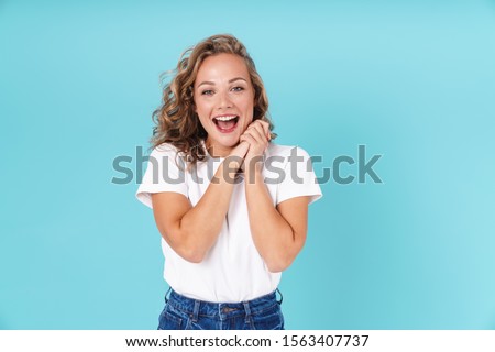 Attractive excited young girl wearing casual clothing standing isolated over blue background, looking at camera