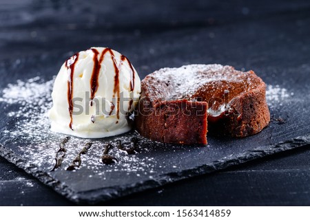 Warm dessert chocolate cake Fondant served on plate with ice-cream ball, cacao. Chocolate lava cake Molten on Dark black background