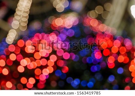 Illuminated abstract round red, orange, blue and gold bokeh on dark background. Colourful glitter bokeh from out of focus view of decoration bulbs.
