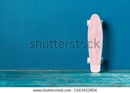 Blank plastic pink skateboard on the floor against blue wall