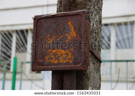 iron old brown electric box in rust hanging on a concrete pillar