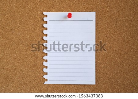 Piece paper of blank white note pad stick push pin red to a cork board. empty space for text write a note.