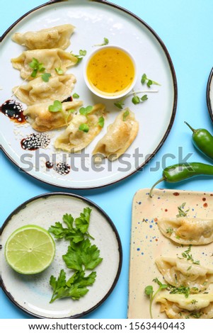 Plates with tasty Japanese gyoza on color background