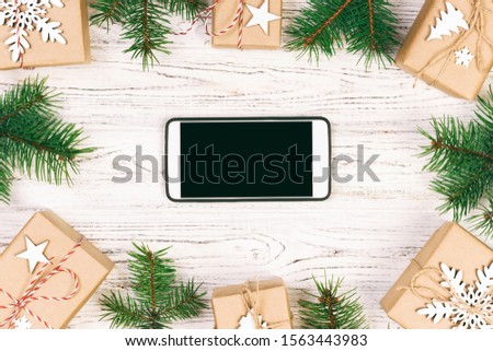 White black smartphone with isolated screen, above wooden desk with Christmas decorations. Top view. Toned.