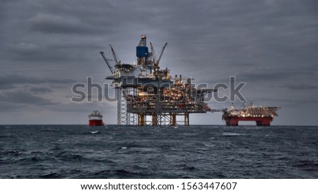 Picture of offshore oil and gas production in the sea in stormy weather at dusk.
Jack up, semi submersible rigs crude oil production in ocean.