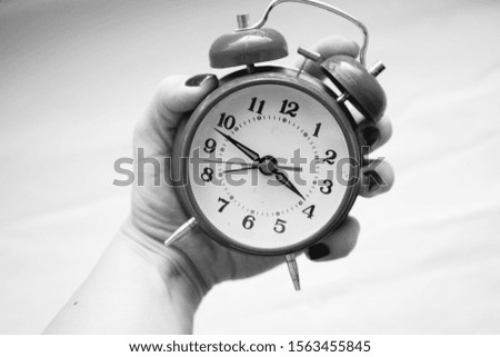     black and white photo alarm clock in hand                           