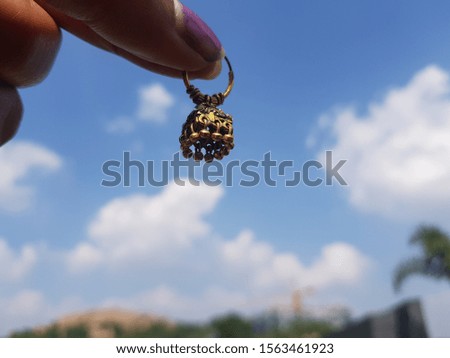  Holding Pair of gold colour metal earring