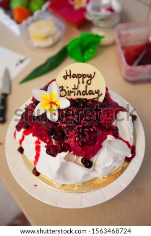 Making Pavlova cake with fruit cream. Greeting celebration happy birthday on cake.