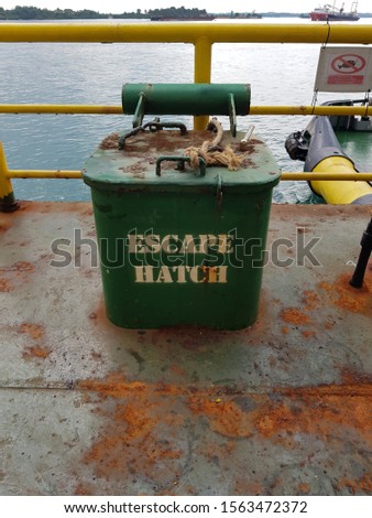 Escape hatch from an engine room on deck of a construction work barge while docked at port