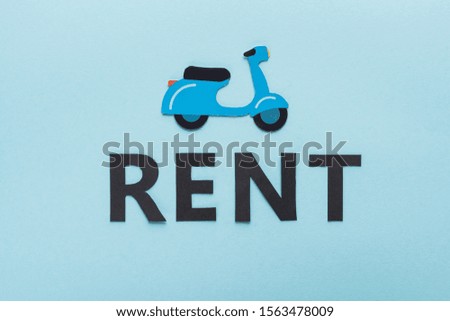 top view of paper cut scooter and black rent lettering on blue background
