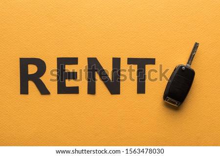 top view of paper cut rent lettering and car key on orange background