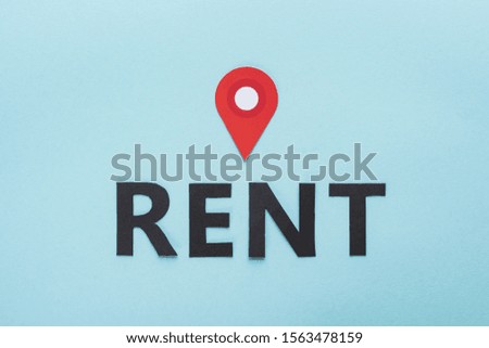 top view of paper cut black rent lettering and red location mark on blue background