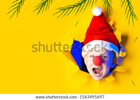 little cheerful Santa in a hat smiles, getting out of the ragged yellow background lit by neon light