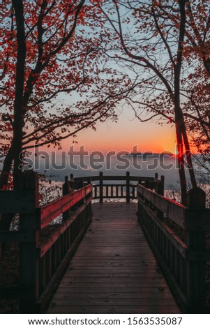 A gorgeous foggy sunrise along a boardwalk viewpoint over the Mississippi River in Pikes Peak State Park, Iowa, USA.  Royalty-Free Stock Photo #1563535087