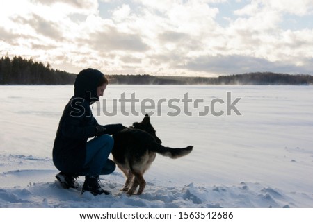 Girl with a dog on the shore of a winter lake. A dog is a man s best friend, and in winter a dog can warm up in any conditions.