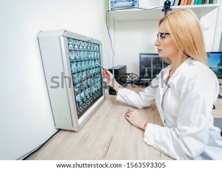 A professional doctor radiologist with gloves is looking at an mri picture on the background of a negatoscope