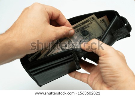 take American dollars from a black leather wallet in his hands, close-up