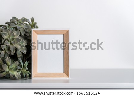 mock up made from photo frame in scandinavian minimalist interior with succulents on gray commode on white background