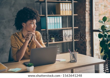 Photo of interested pensive cute charming mixed-race business woman in yellow shirt looking out window in search of new ideas to realize in her project