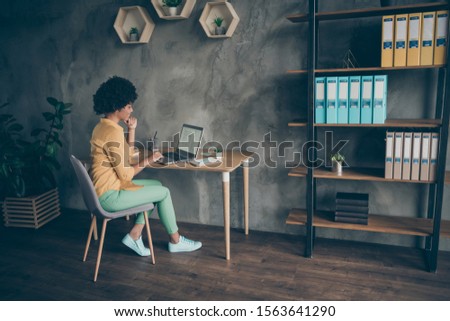 Back rear spine full length profile side photo of confident afro american girl expert sit table work laptop read information think decide choose solution in office loft workstation