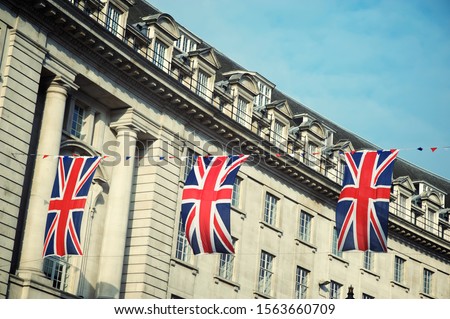 Union Jack flag decorations strung above the streets of London, UK under soft blue sky