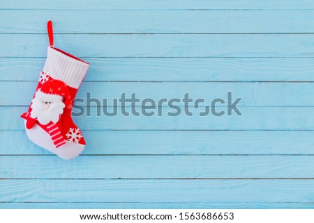 Christmas stocking with gifts hanging on blue wooden background