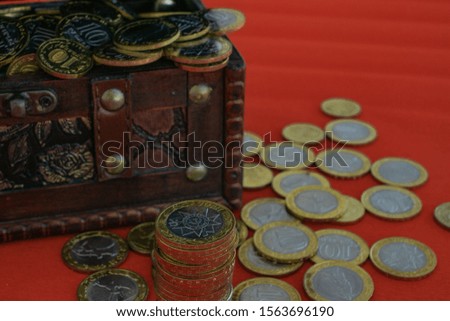 open chest filled with coins. column of coins in front. coins around the chest.