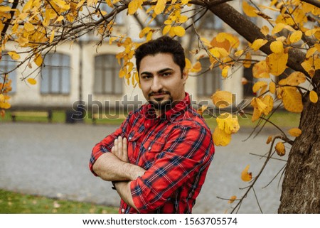 man in a plaid shirt with a clock on the background of an old building