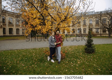 couple in love looks into the distance against the background of a yellow tree in the park