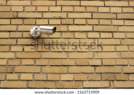 White security surveillance camera on a brick wall.