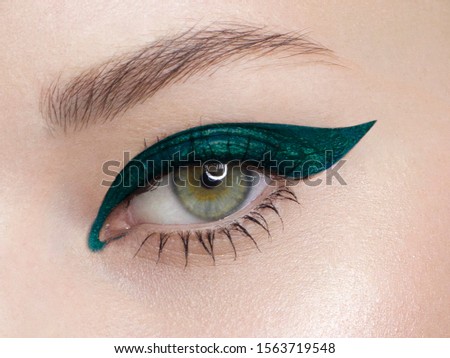 Glamour close-up portrait of beautiful woman model face with winged bright green eyeliner make-up, clean skin on white background. Long eyelashes and thick eyebrows. Royalty-Free Stock Photo #1563719548