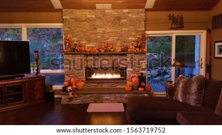 Large Stone Fireplace with Flames, at Dusk in a Rustic Home During the Fall Season Royalty-Free Stock Photo #1563719752