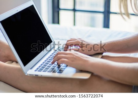 Young woman usign her laptop with black screen while lying on the bed at home.  Lifestyle concept